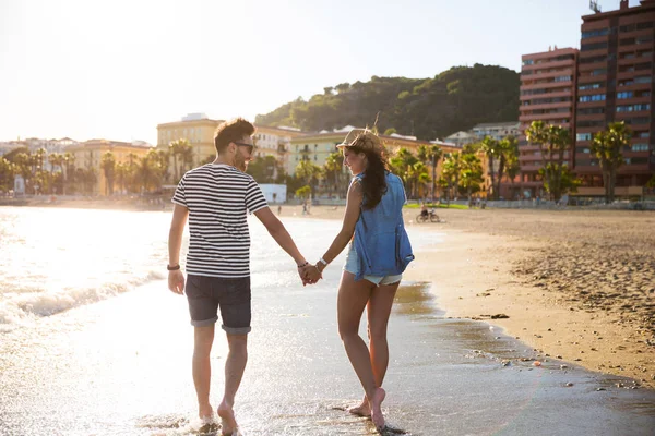 Happy couple walking in water holding hands — Stock Photo, Image