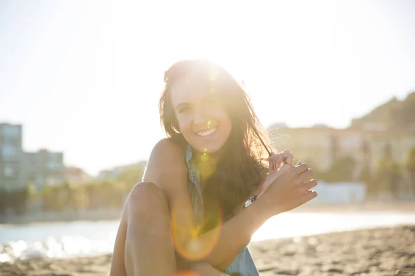 Jovem mulher bonita sentada na praia sorrindo — Fotografia de Stock