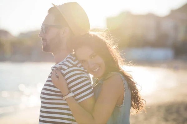 Mujer joven abrazando a su novio en la playa sonriendo — Foto de Stock