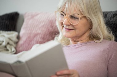 Mutlu üst düzey Bayan rahat oturuyor kitap okumak