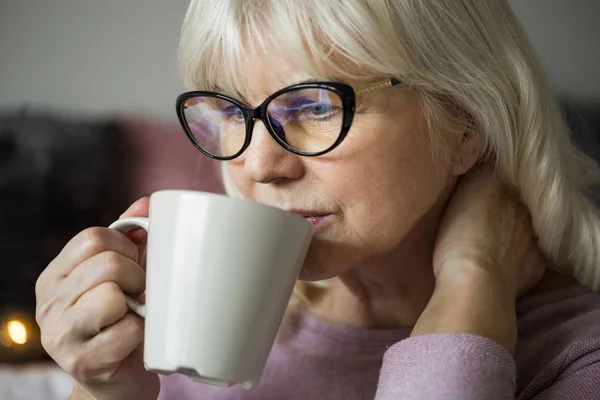 Pensativo señora mayor en vasos de tomar una taza de té —  Fotos de Stock