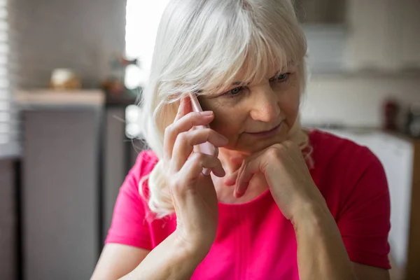 Pensativo señora mayor escuchando la conversación telefónica atentamente — Foto de Stock