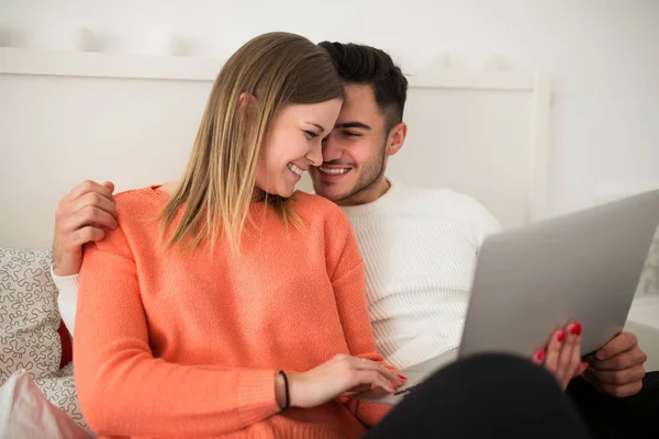 Jonge gelukkige paar met behulp van laptop op bed — Stockfoto