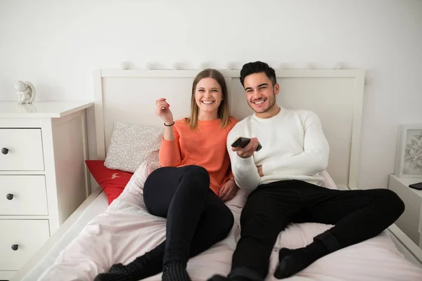 Šťastný pár ležící na posteli, sledování televize — Stock fotografie