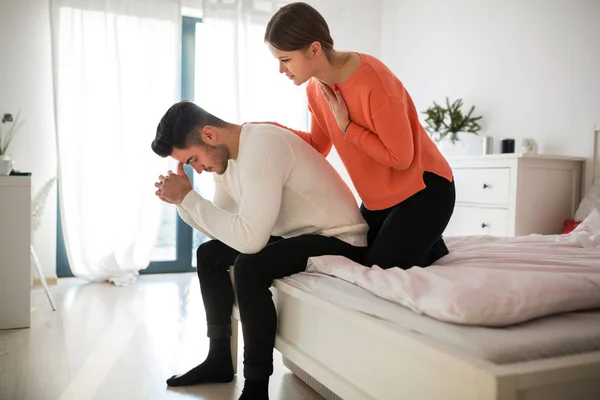 Upprörd man som satt på sängen och hans flickvän trösta honom — Stockfoto
