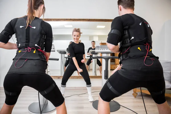 Entrenamiento entrenador feliz hombre y mujer con dispositivos ems — Foto de Stock