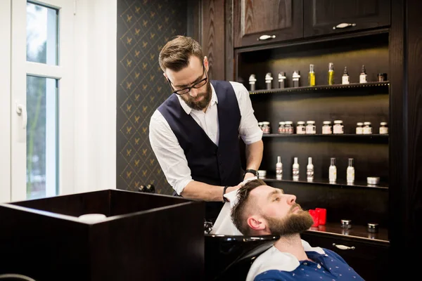 Peluquero joven limpiando el cabello del cliente con toalla — Foto de Stock