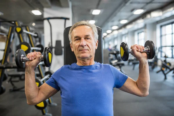 Hombre mayor levantando pesas en máquina de fuerza de martillo — Foto de Stock