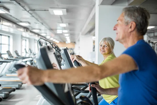 Happy senior woman training on stair stepper at gym