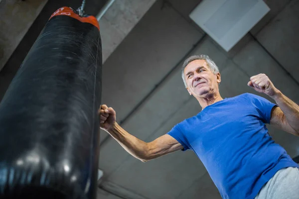 Entrenamiento de hombre mayor seguro en saco de boxeo — Foto de Stock