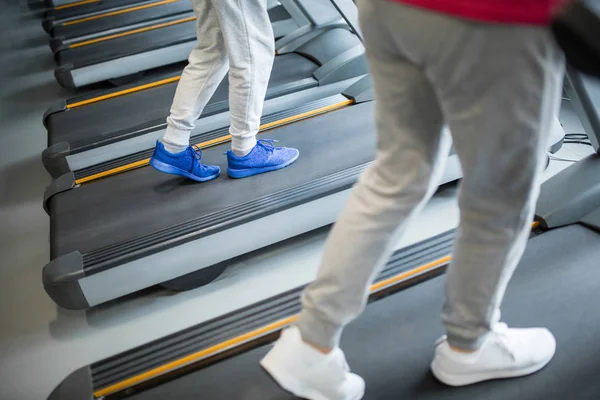 Personas piernas caminando en la cinta de correr en el gimnasio — Foto de Stock