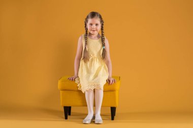 Sarı kabarık üzerinde oturan genç mutlu kız