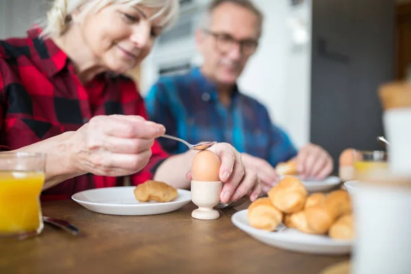 Mulher sênior quebrando ovo cozido para o café da manhã — Fotografia de Stock