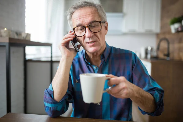 Homem sênior falando no celular na cozinha — Fotografia de Stock
