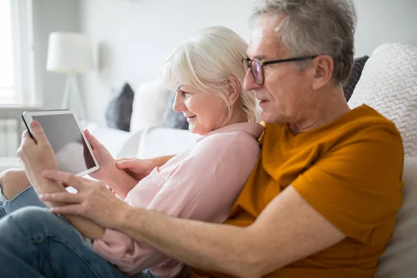Feliz pareja de ancianos leyendo ebook juntos — Foto de Stock