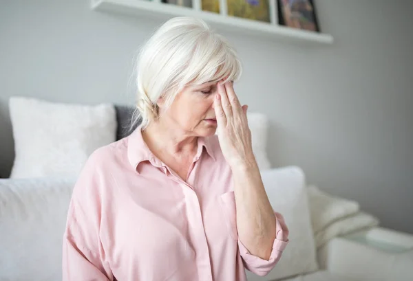 Señora mayor con migraña tocándose la frente — Foto de Stock