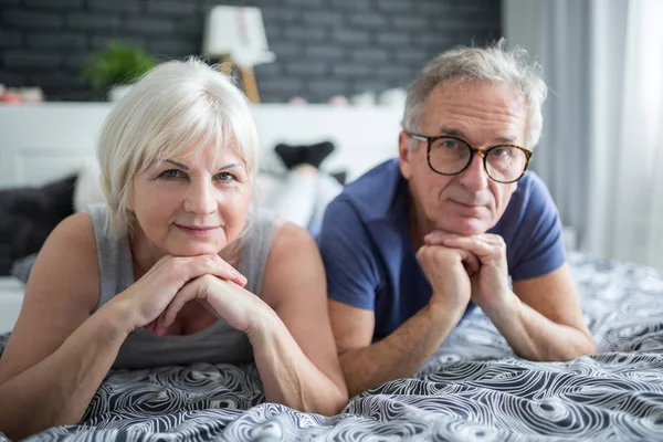 Senior paar liggend op bed stutten hoofden op handen — Stockfoto