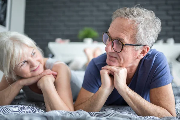 Senior feliz pareja acostada en la cama mirándose — Foto de Stock