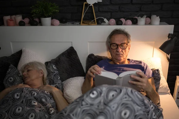 Hombre mayor leyendo libro en la cama antes de dormir — Foto de Stock