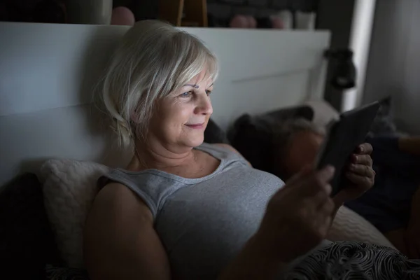 Feliz señora mayor usando la tableta en la cama — Foto de Stock