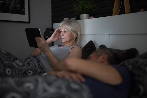 Mujer mayor feliz usando tableta en la cama por la noche — Foto de Stock