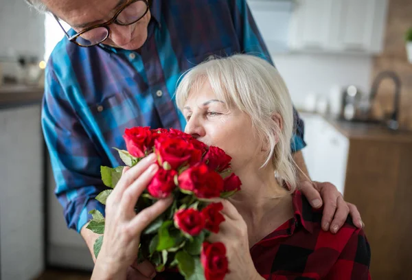 Mulher sênior segurando um monte de rosas de seu marido Fotos De Bancos De Imagens