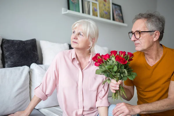 Senior man geven van zijn vrouw bloemen voor excuses Stockfoto