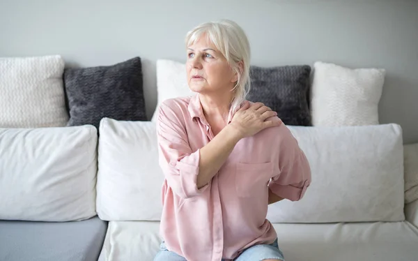 Senior senhora com dor nas costas sentado no sofá Fotografias De Stock Royalty-Free