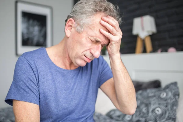 Senior man met migraine die hand op het voorhoofd Stockfoto