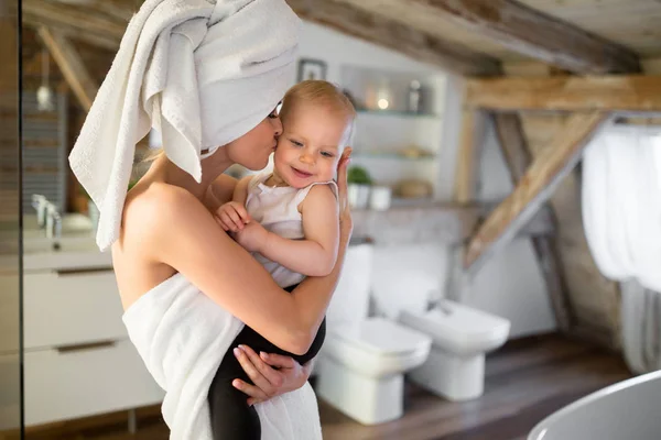 Gelukkige moeder die haar baby in de Wang zoenen Stockfoto