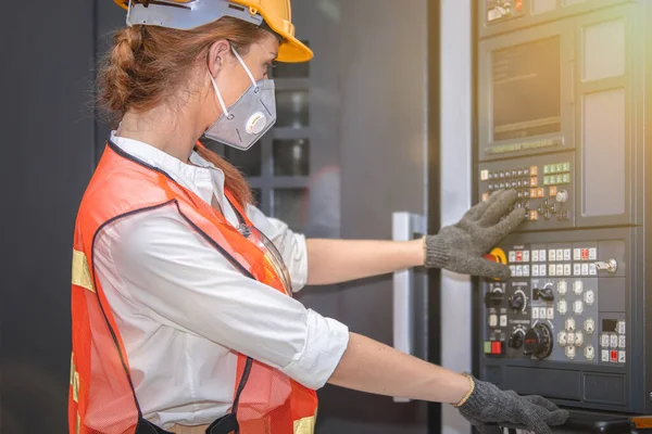 Young woman engineer in the mask protected herself with air pollution & virus with controller machine on blurred factory background