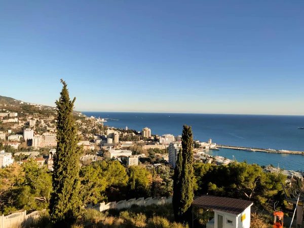 Dağdan şehre geniş selvi ağaçları ve deniz manzarası