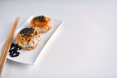 Çin fasulye ezmeli kekler ve yemek çubukları seramik tabakta, beyaz arka planda izole edilmiş.