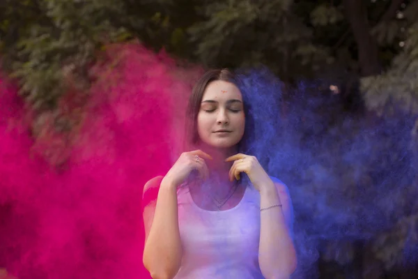 Pretty woman with colored powder exploding around her — Stock Photo, Image