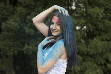 Gülümseyen omuzları üzerinde renkli toz ile esmer kadın