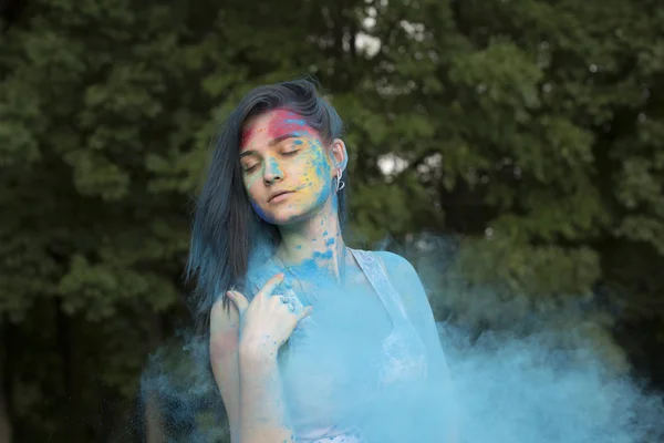 Brunette woman with colored powder around her — Stock Photo, Image