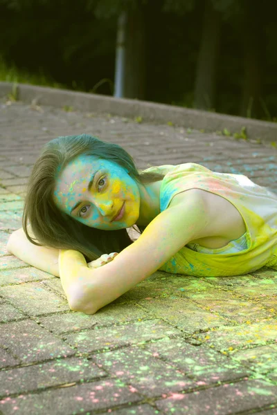 Усміхнена модель лежить на тротуарі з кольоровим порошком — стокове фото