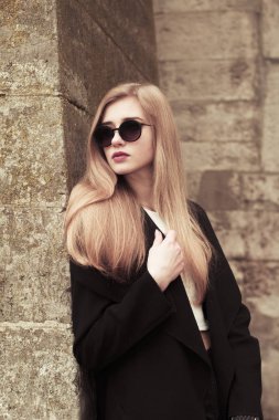 Tuğla duvar, siyah gözlüklü moda modeli
