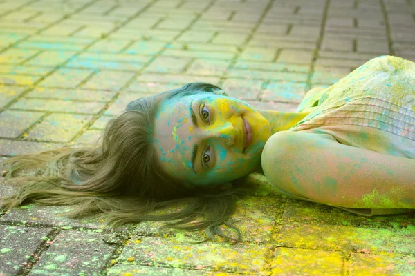 Ganska ung modell ligger på trottoaren med pulver Holi — Stockfoto