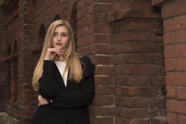 Tuğla duvar, rahat tarzı giymiş güzel sarışın kadın