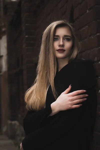 Wanita pirang cantik dengan mantel hangat di dekat dinding bata — Stok Foto