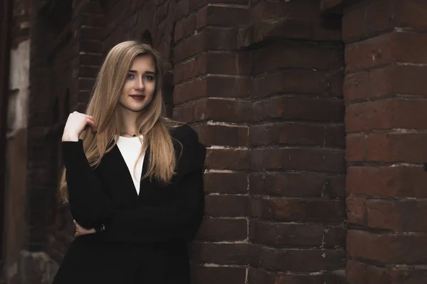 Mujer rubia de moda vestida en estilo casual en la pared de ladrillo —  Fotos de Stock