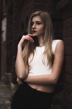 Tuğla duvar, rahat tarzı giymiş güzel sarışın kadın