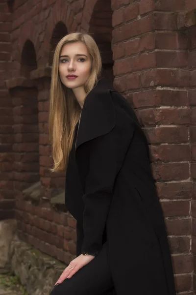 Glamour-Blondine im warmen Mantel in der Nähe einer Ziegelwand — Stockfoto