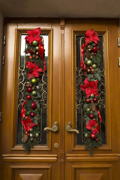 Door decorated of fir, flowers and balls. Christmas decor