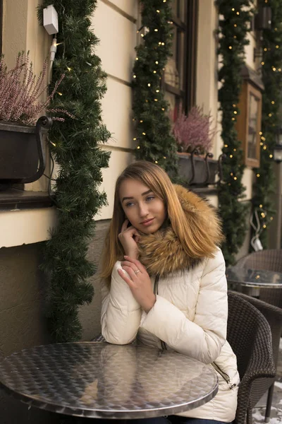 Linda mulher sentada no café com um fundo de luzes embaçadas — Fotografia de Stock