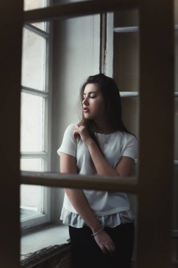 Pencerenin duran çekici genç esmer kadın