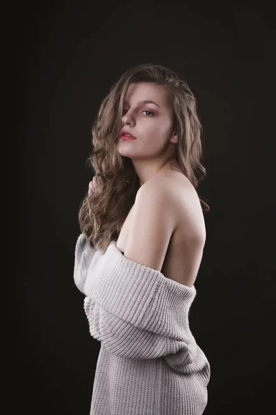 Mujer joven sensual posando en suéter con hombros desnudos —  Fotos de Stock