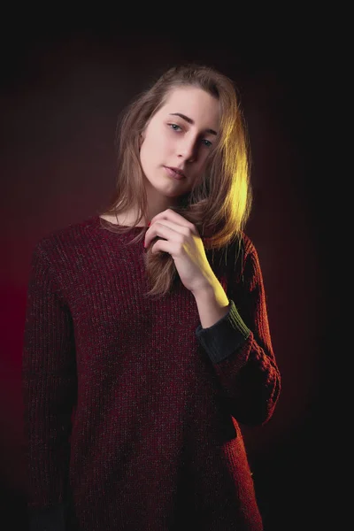 Нежная молодая женщина в вязаном красном свитере позирует в студии — стоковое фото