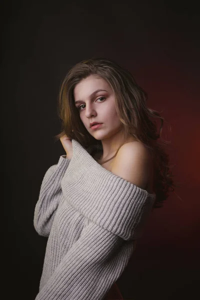 Модная молодая женщина позирует в свитере в темной комнате — стоковое фото